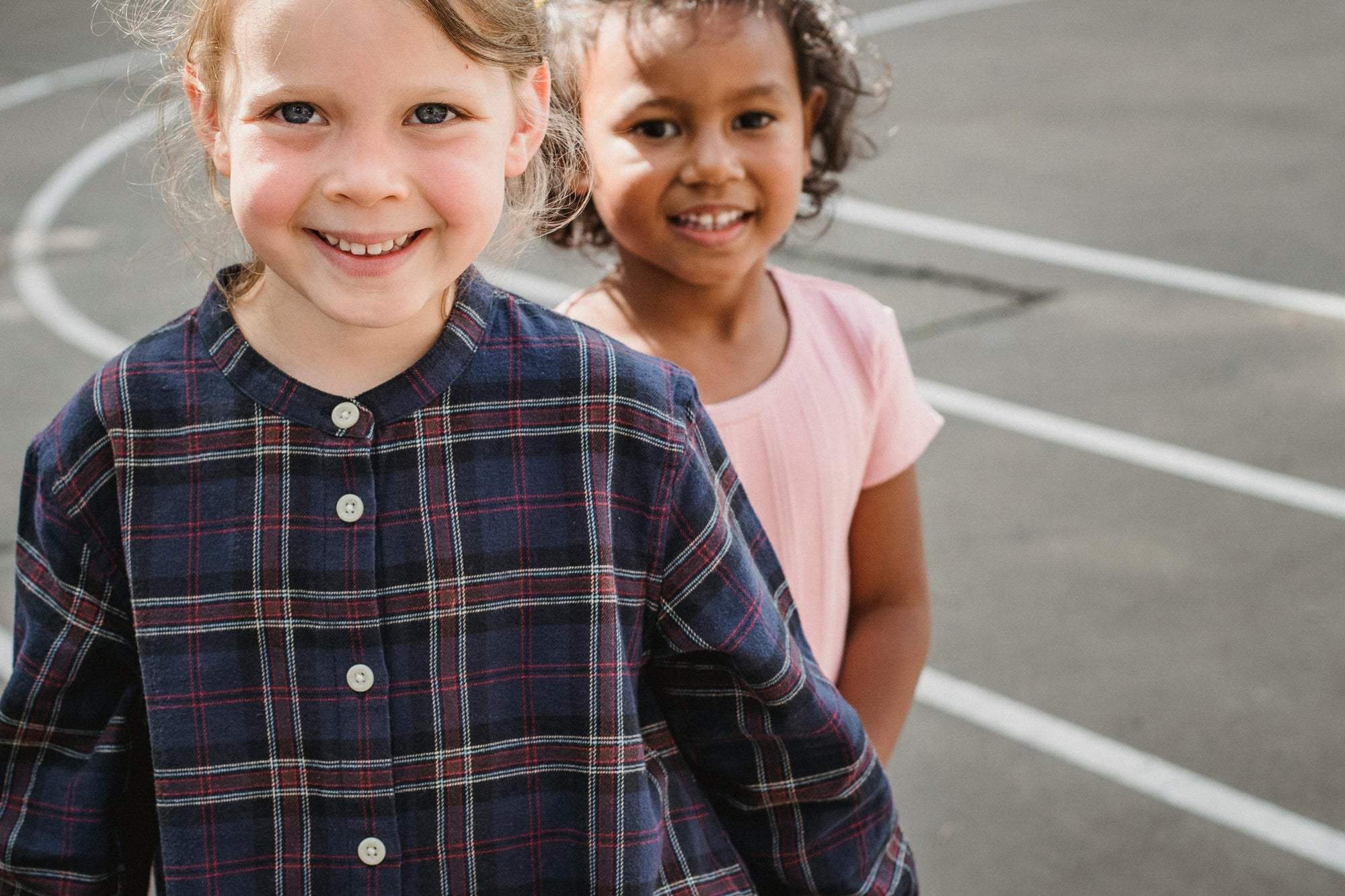 Two children standing on a playground with a clear sky background